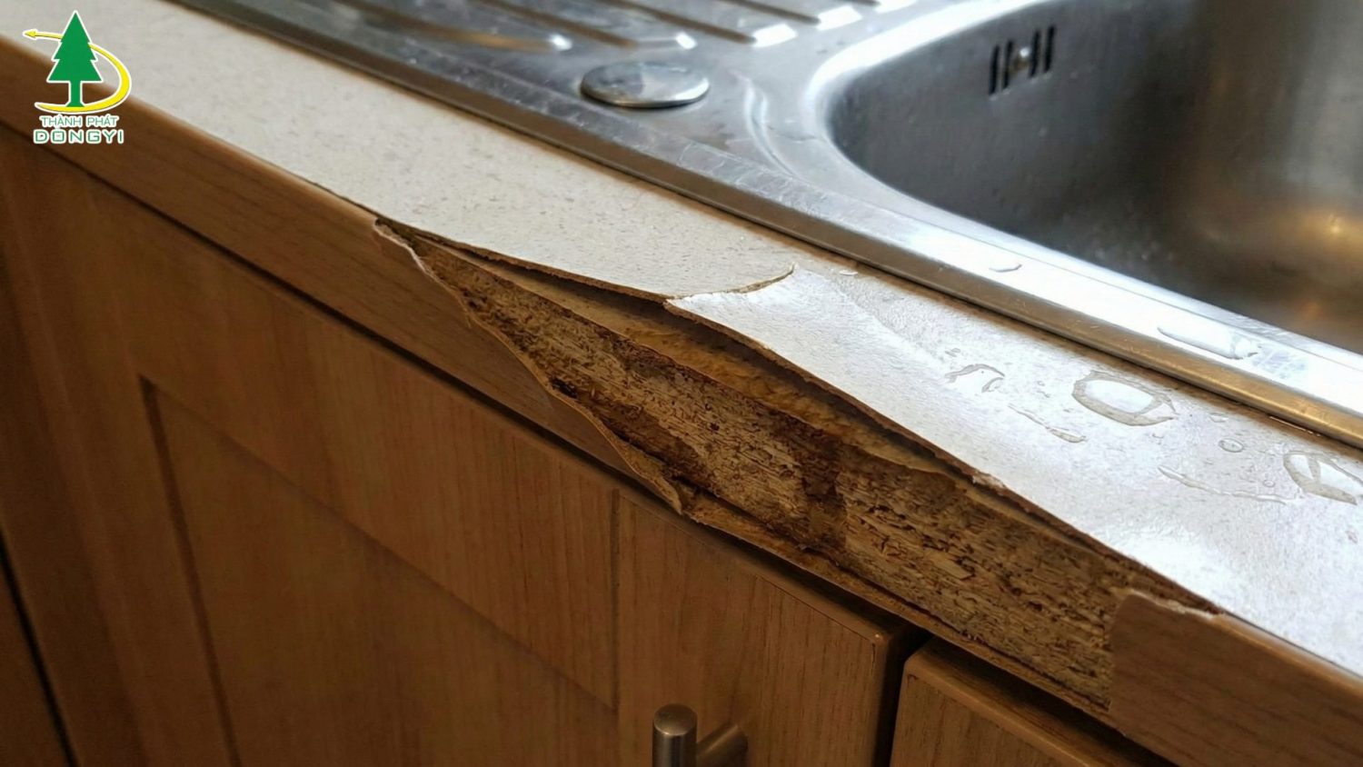 Cận cảnh bong mép tủ bếp hoặc bong cạnh MDF gần chậu rửa